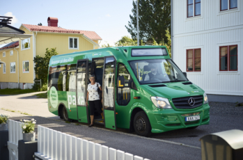kvinna kliver ur mindre buss i villaområde
