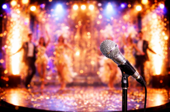 En glittrig scen i guld och rosa, med artister i bakgrunden och en mikrofon i förgrunden.